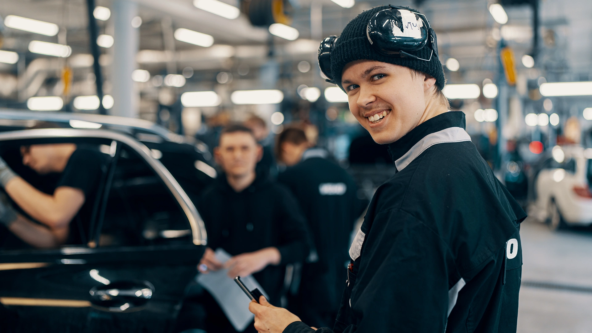 Jauns vīrietis automehāniķis stāv Veho servisa centrā pie Mercedes-Benz automašīnas