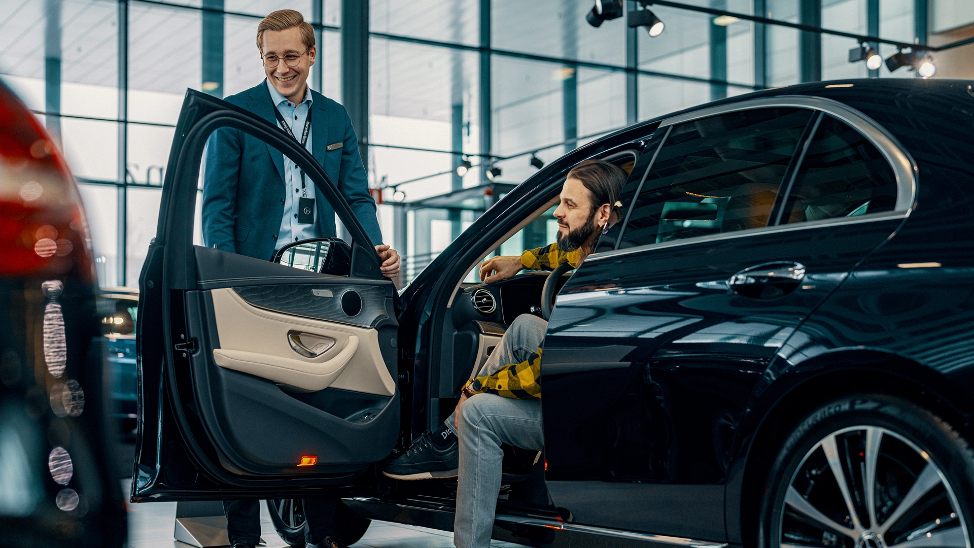 Klients un auto pārdevējs apskata Mercedes-Benz vieglo automašīnu