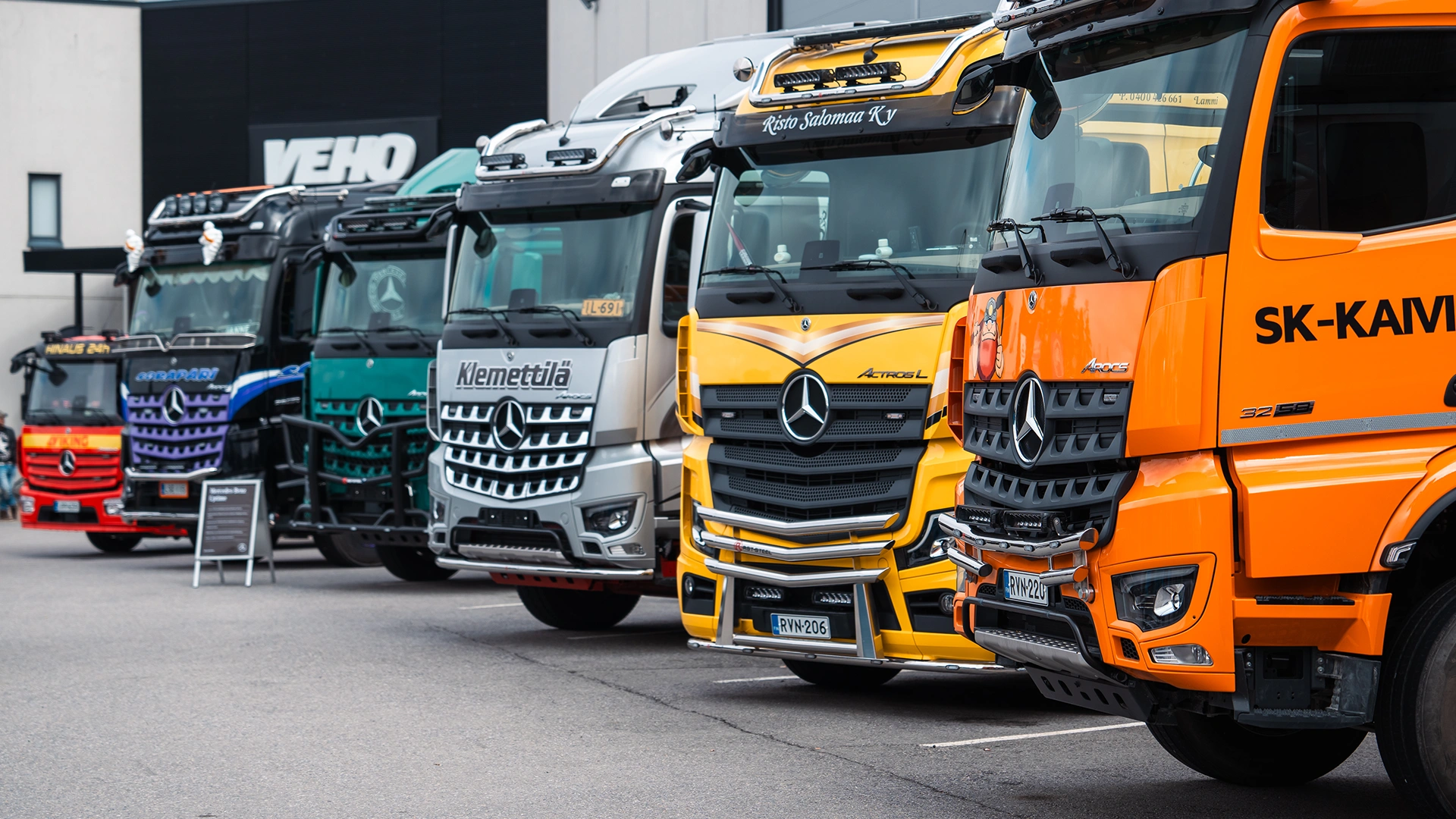 Kravas automašīnas dažādās krāsās noparkotas vienā rindā