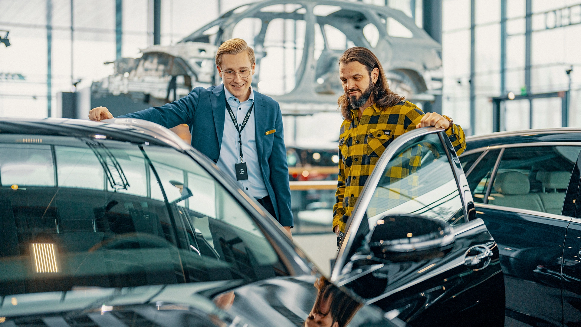 Pārdevējs ar klientu pie jaunas Mercedes-Benz automašīnas Veho auto salonā