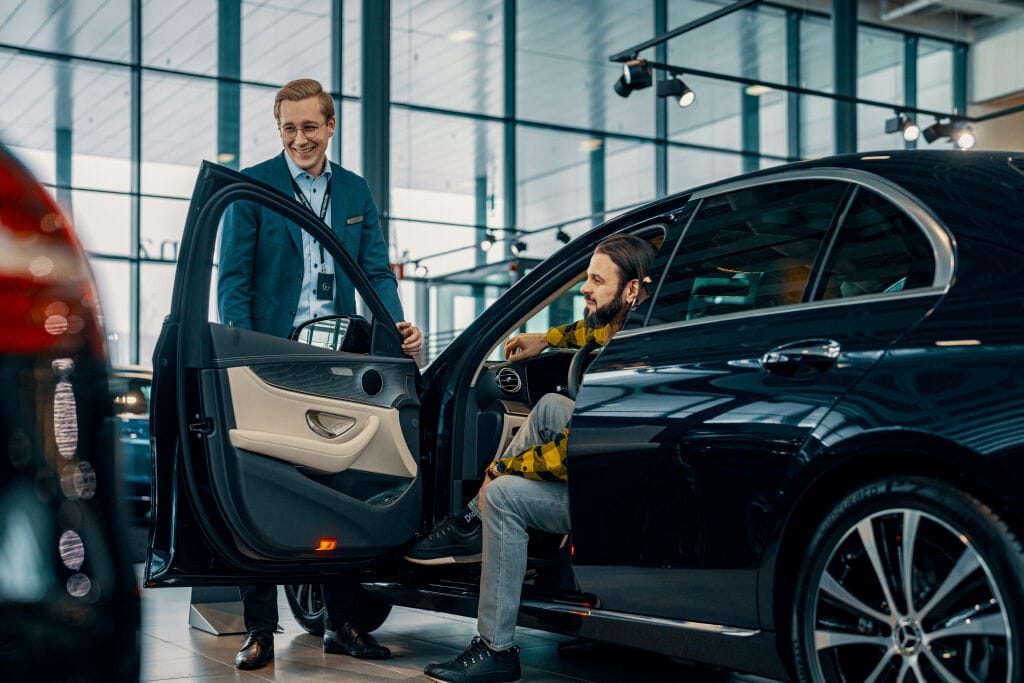 Klients un pārdevējs sarunājas Mercedes-benz auto