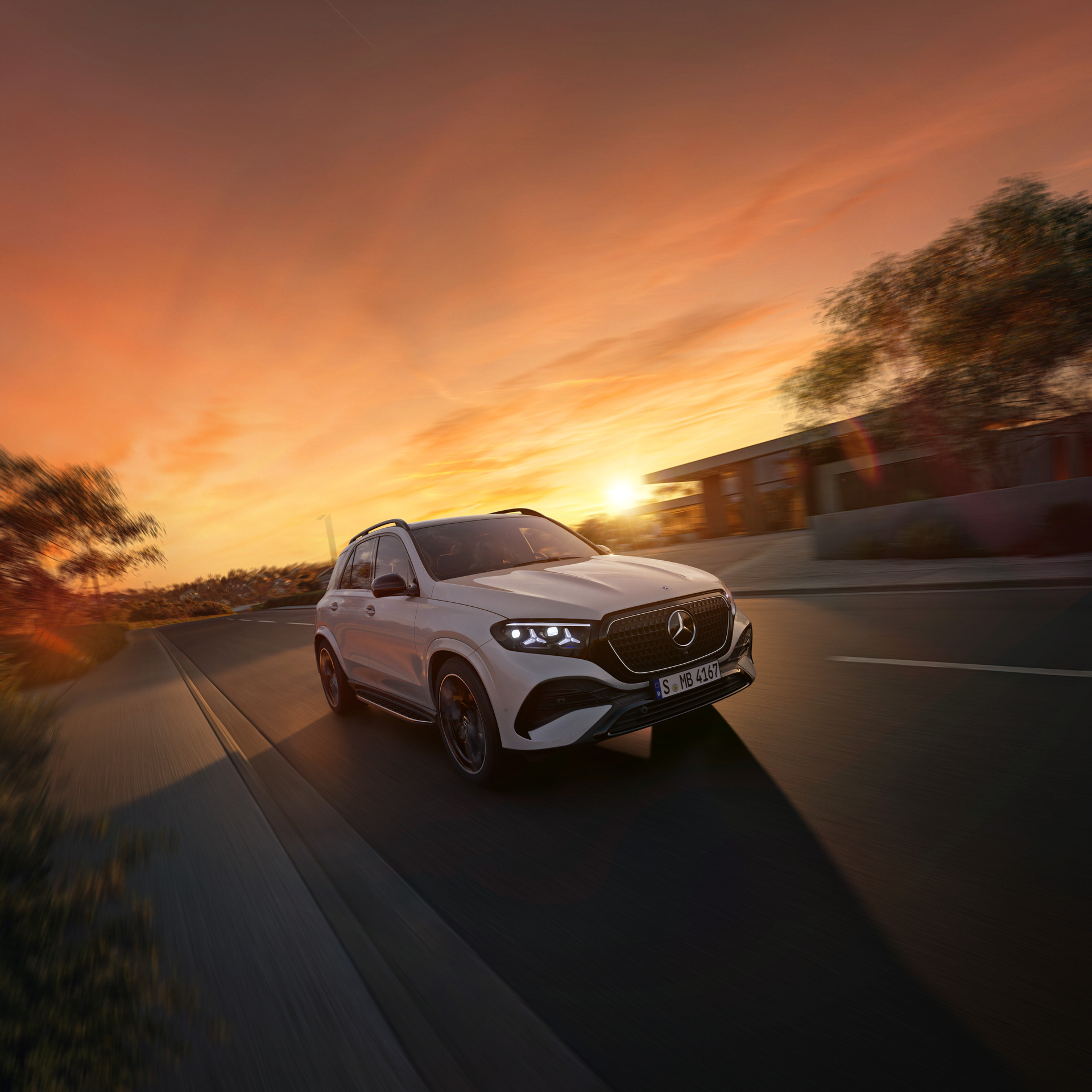 Balts Mercedes-Benz GLE brauc pa ceļu saulrietā